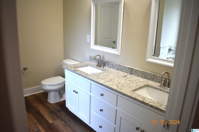 bathroom featuring double vanity, wood-type flooring, and toilet