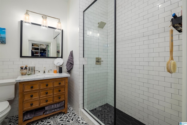 bathroom featuring tile walls, walk in shower, toilet, and vanity with extensive cabinet space