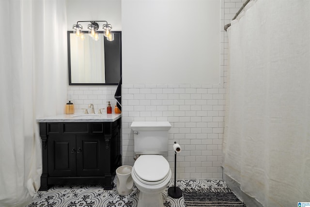 bathroom with tile flooring, vanity, toilet, and tile walls