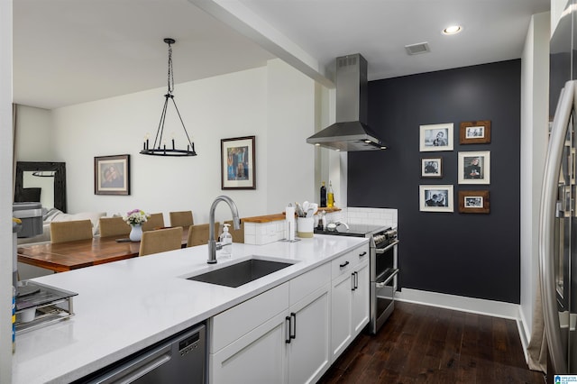 kitchen featuring appliances with stainless steel finishes, white cabinets, dark hardwood / wood-style floors, wall chimney exhaust hood, and sink