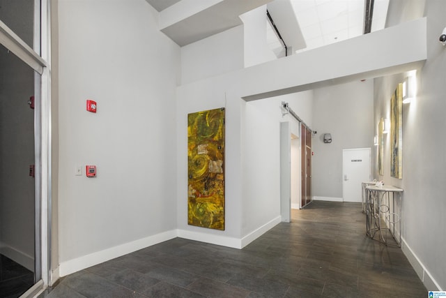 corridor featuring a towering ceiling and dark wood-type flooring