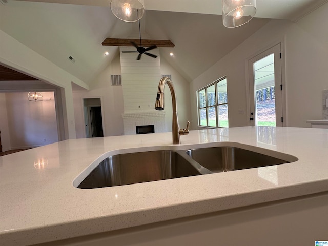 kitchen with ceiling fan, vaulted ceiling, a fireplace, pendant lighting, and sink