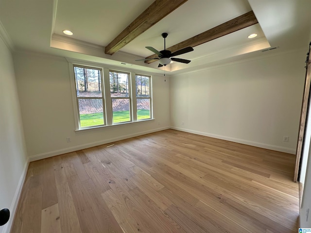 empty room with beam ceiling, ornamental molding, a barn door, light wood-type flooring, and ceiling fan