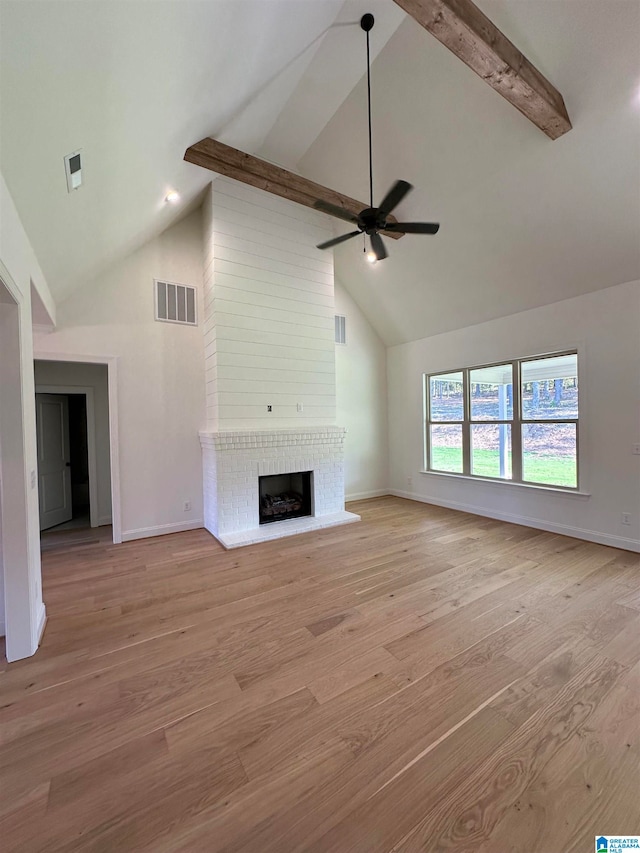 unfurnished living room featuring light hardwood / wood-style flooring, ceiling fan, high vaulted ceiling, and a brick fireplace