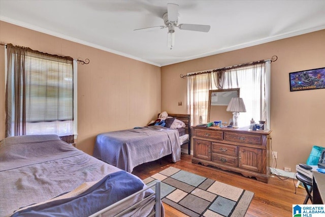 bedroom with ornamental molding, wood-type flooring, and ceiling fan