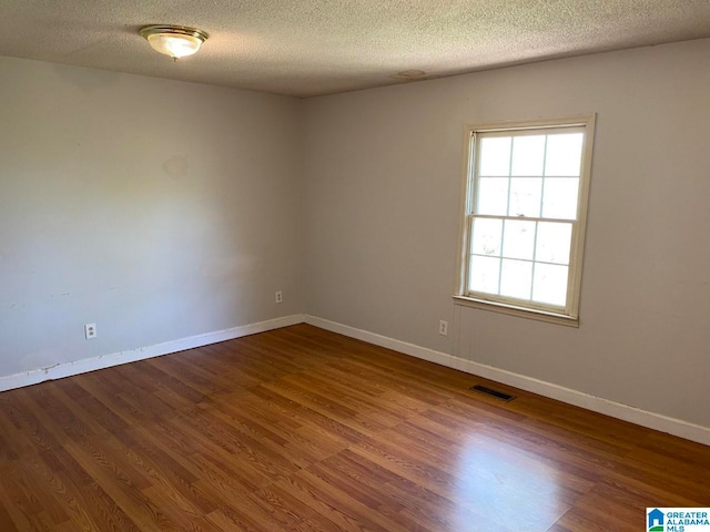 spare room featuring a textured ceiling and dark hardwood / wood-style flooring