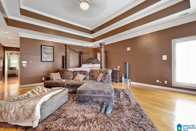 bedroom featuring light hardwood / wood-style floors, multiple windows, crown molding, and a raised ceiling