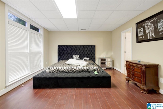 bedroom with a drop ceiling and hardwood / wood-style floors