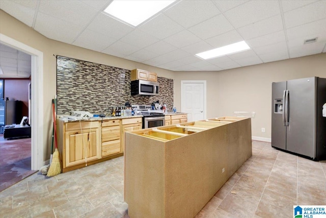 kitchen featuring backsplash, a center island, light brown cabinets, and appliances with stainless steel finishes