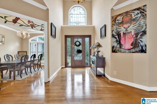 foyer entrance with crown molding, hardwood / wood-style floors, a chandelier, and a high ceiling