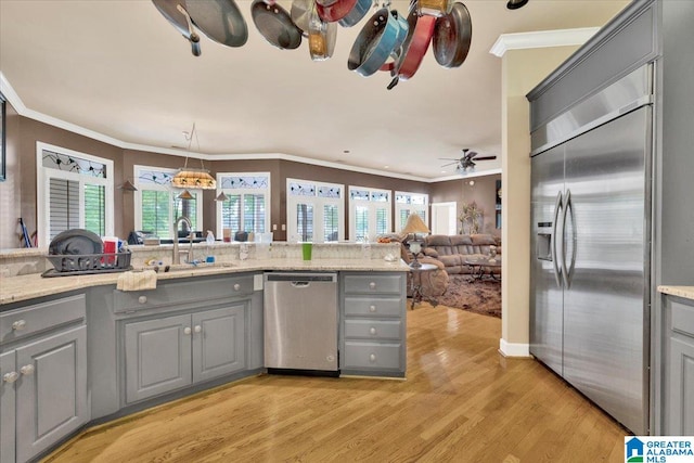 kitchen with ornamental molding, gray cabinets, stainless steel appliances, and light hardwood / wood-style floors