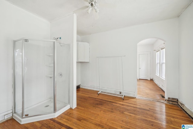 bathroom featuring a shower with shower door, hardwood / wood-style floors, and ceiling fan