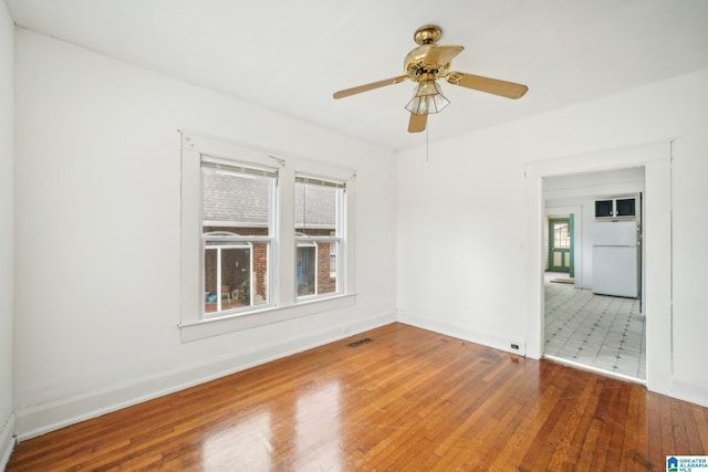 spare room featuring ceiling fan, a healthy amount of sunlight, and wood-type flooring