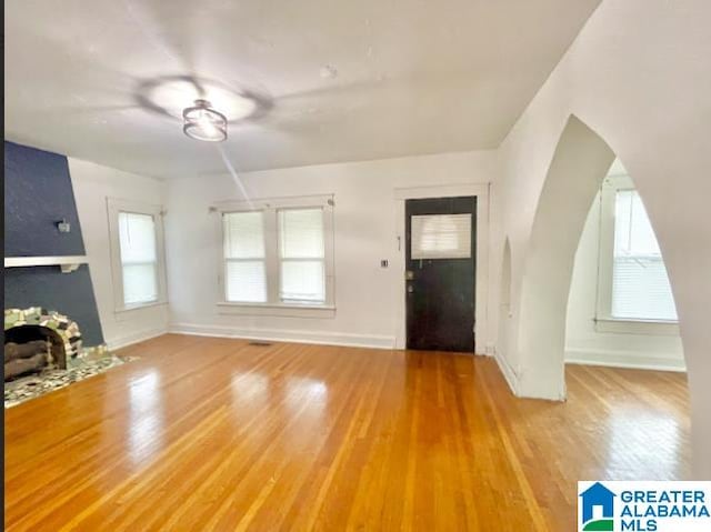 interior space with hardwood / wood-style flooring, a healthy amount of sunlight, and a large fireplace