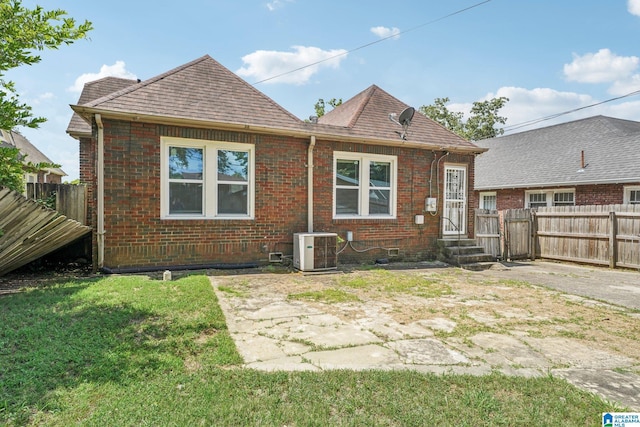 back of property with cooling unit, a patio area, and a lawn