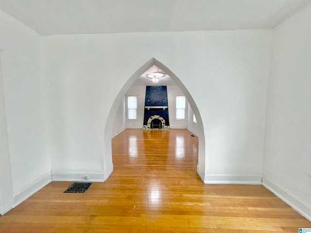 additional living space featuring hardwood / wood-style flooring and a brick fireplace