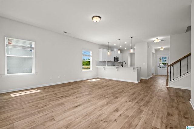 unfurnished living room with light wood-type flooring and sink