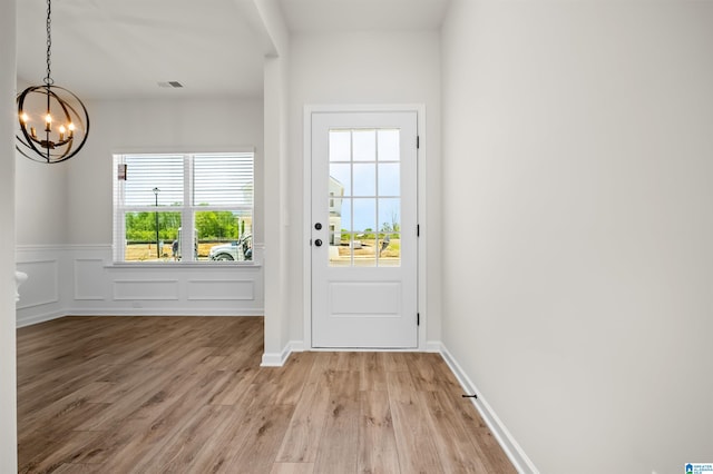 doorway with a chandelier and light wood-type flooring