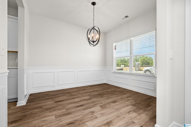 unfurnished dining area with hardwood / wood-style flooring and a notable chandelier