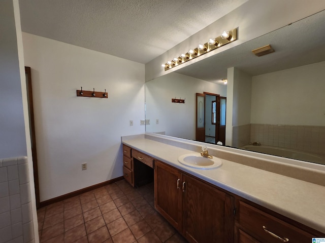 bathroom with tile flooring, a bathing tub, vanity, and a textured ceiling