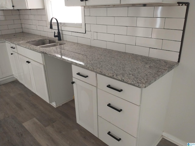 kitchen featuring dark wood-type flooring, white cabinets, light stone counters, sink, and tasteful backsplash