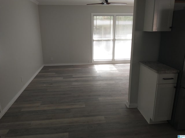 unfurnished dining area featuring dark hardwood / wood-style floors, ceiling fan, and crown molding