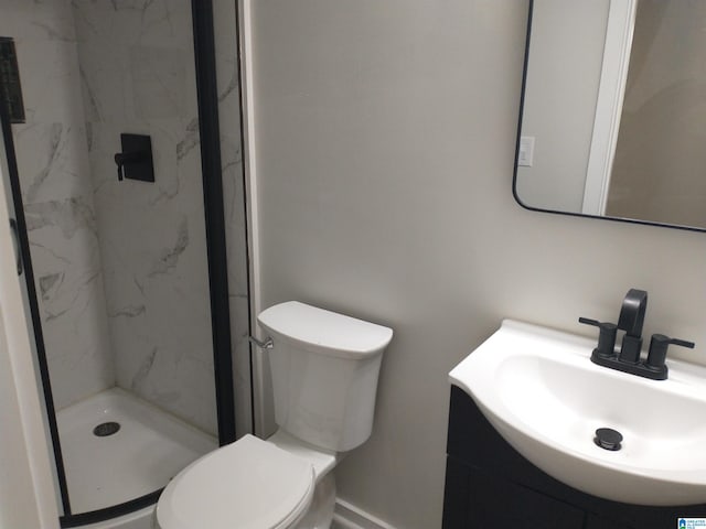 bathroom featuring a tile shower, vanity, and toilet