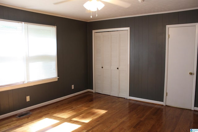 unfurnished bedroom featuring a closet, ceiling fan, dark hardwood / wood-style floors, and crown molding