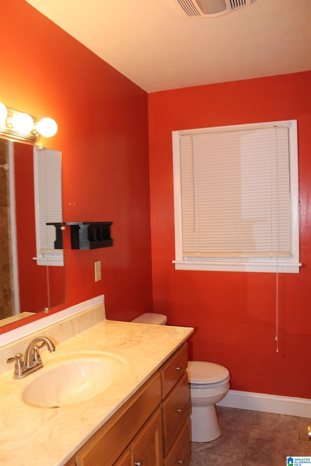 bathroom featuring tile flooring, vanity, and toilet