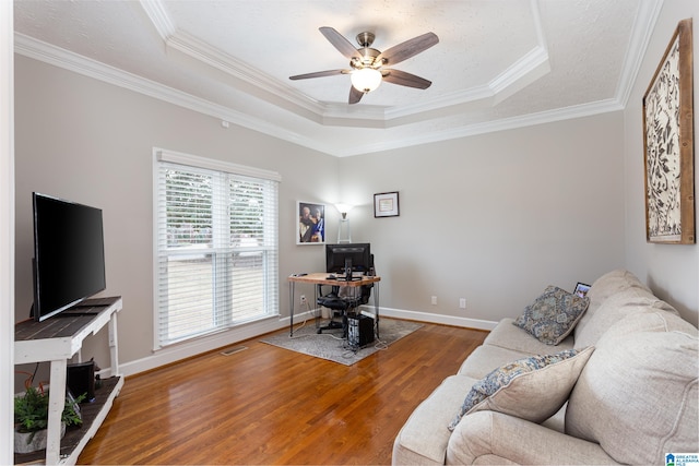 living room featuring ceiling fan, a raised ceiling, wood-type flooring, and crown molding