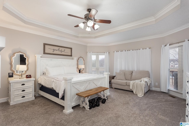 carpeted bedroom featuring ornamental molding, a tray ceiling, and multiple windows