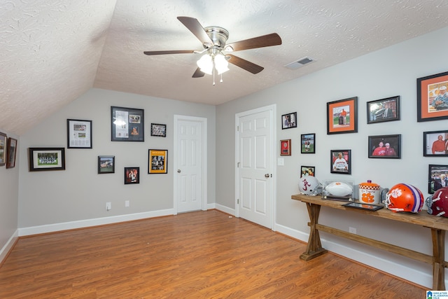 interior space with vaulted ceiling, ceiling fan, a textured ceiling, and hardwood / wood-style flooring