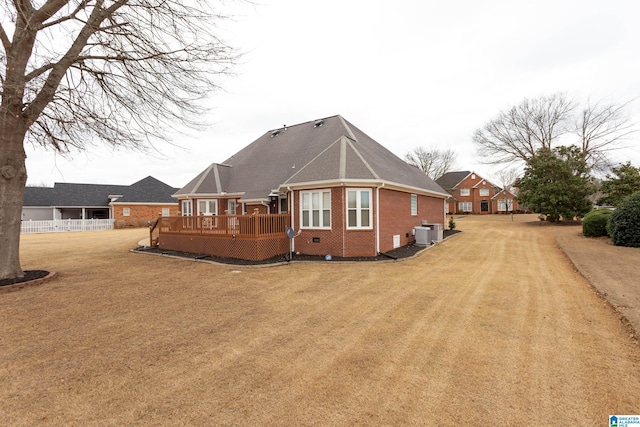 rear view of house featuring a lawn, central AC unit, and a deck