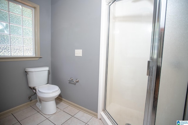 bathroom featuring a shower with door, tile flooring, and toilet