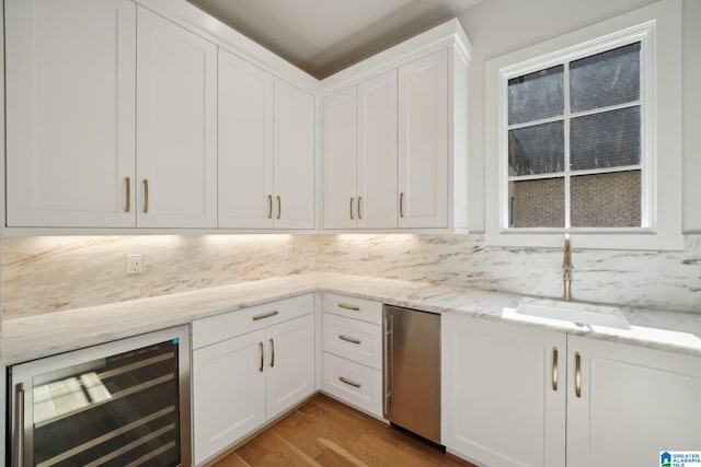 kitchen featuring tasteful backsplash, beverage cooler, sink, light hardwood / wood-style flooring, and white cabinets