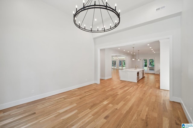 unfurnished living room with a chandelier and light wood-type flooring