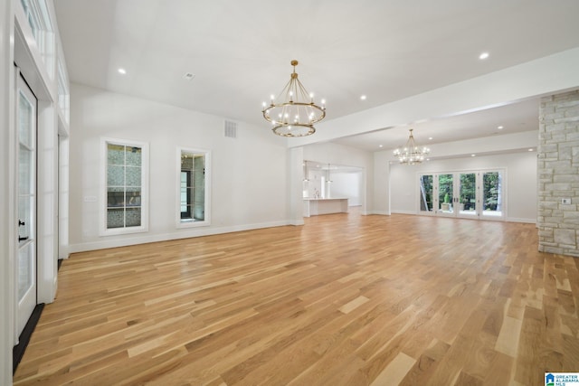 unfurnished living room with light wood-type flooring and an inviting chandelier