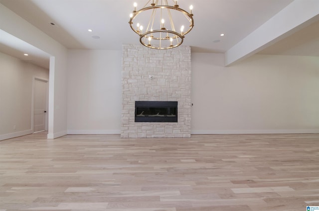 unfurnished living room featuring beamed ceiling, a notable chandelier, light hardwood / wood-style floors, and a stone fireplace