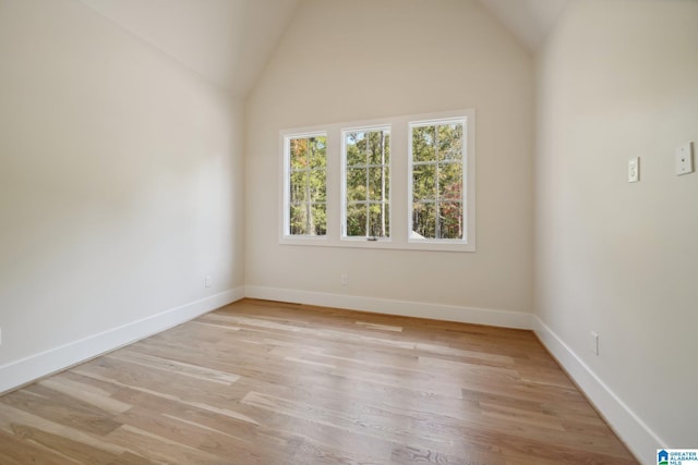 empty room with light wood-type flooring and vaulted ceiling