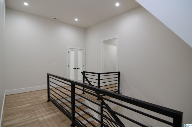 staircase with wood-type flooring and a towering ceiling