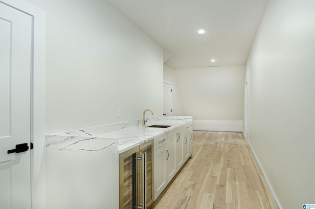 interior space featuring white cabinets, light hardwood / wood-style floors, light stone counters, and sink