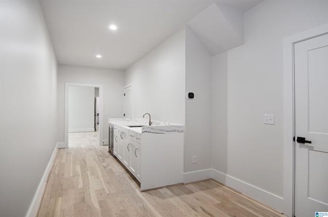 clothes washing area featuring light hardwood / wood-style flooring and sink