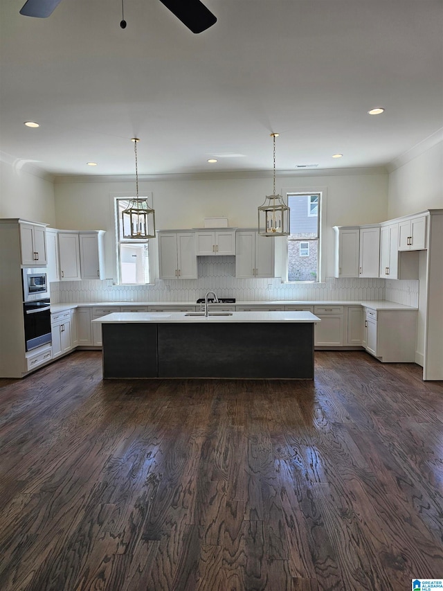 kitchen with hanging light fixtures, dark wood-type flooring, appliances with stainless steel finishes, and ceiling fan