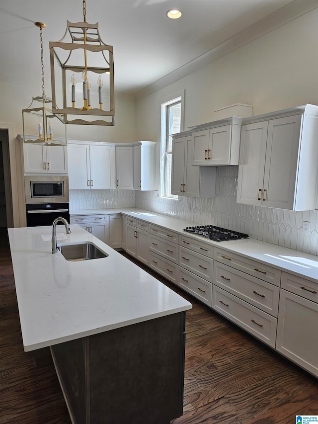 kitchen featuring dark hardwood / wood-style flooring, backsplash, hanging light fixtures, sink, and appliances with stainless steel finishes