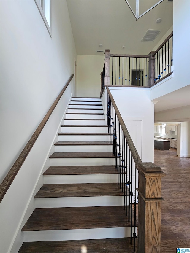 stairway featuring hardwood / wood-style floors and a high ceiling