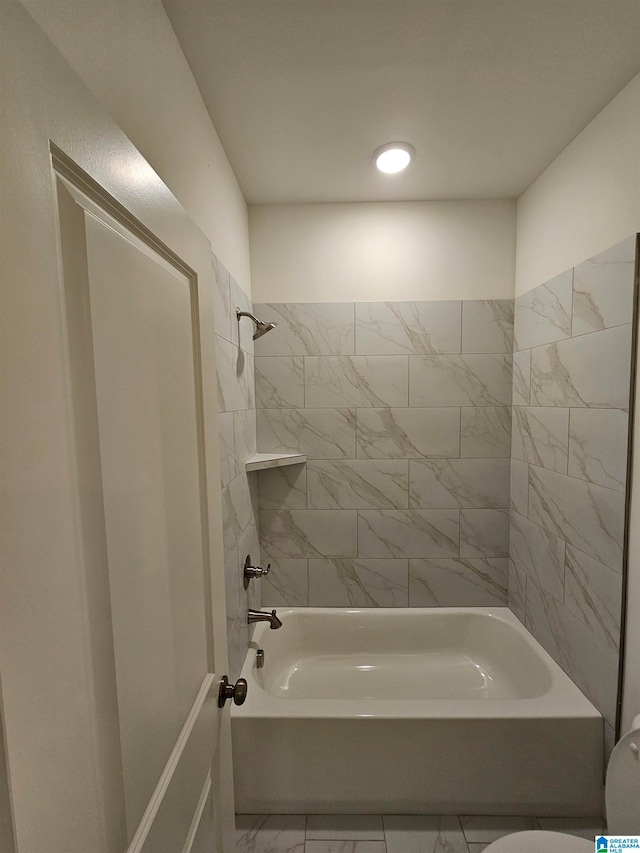 bathroom featuring tile floors, toilet, and tiled shower / bath combo