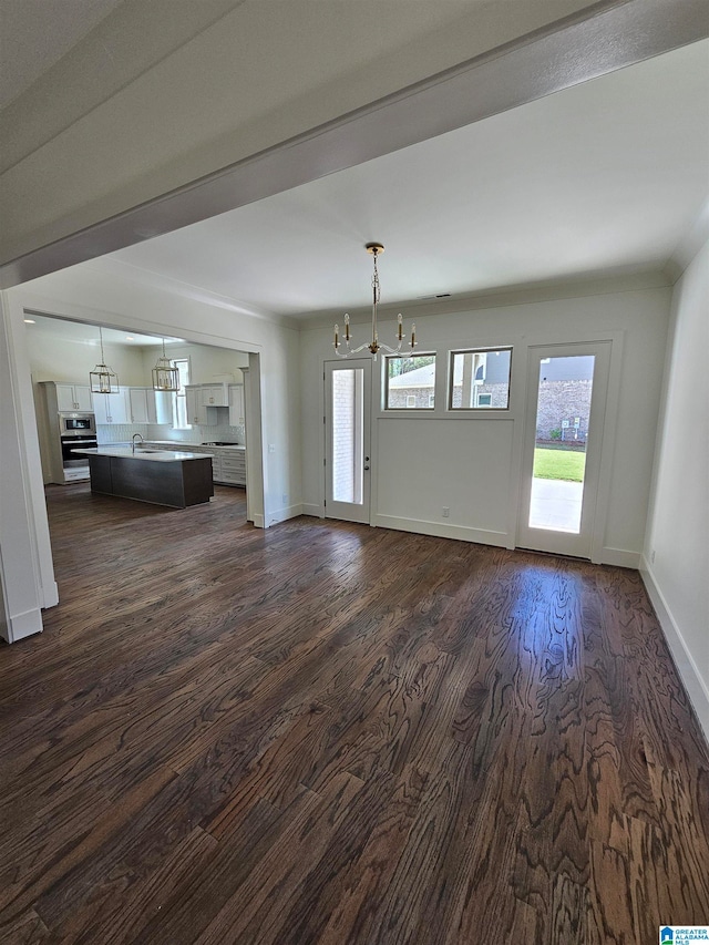 unfurnished living room featuring a notable chandelier, sink, and dark hardwood / wood-style flooring