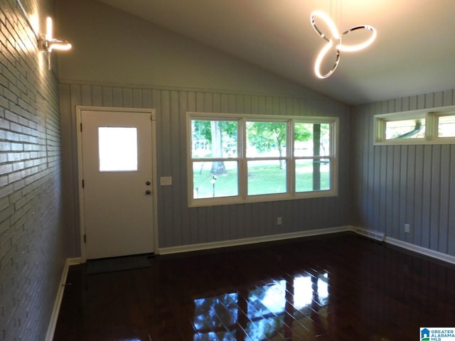 entryway featuring dark hardwood / wood-style floors, lofted ceiling, and brick wall