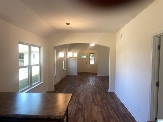 unfurnished dining area with a healthy amount of sunlight, vaulted ceiling, and dark hardwood / wood-style flooring