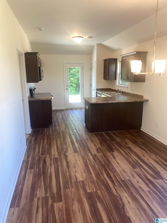 kitchen with dark hardwood / wood-style floors, kitchen peninsula, decorative light fixtures, and dark brown cabinetry